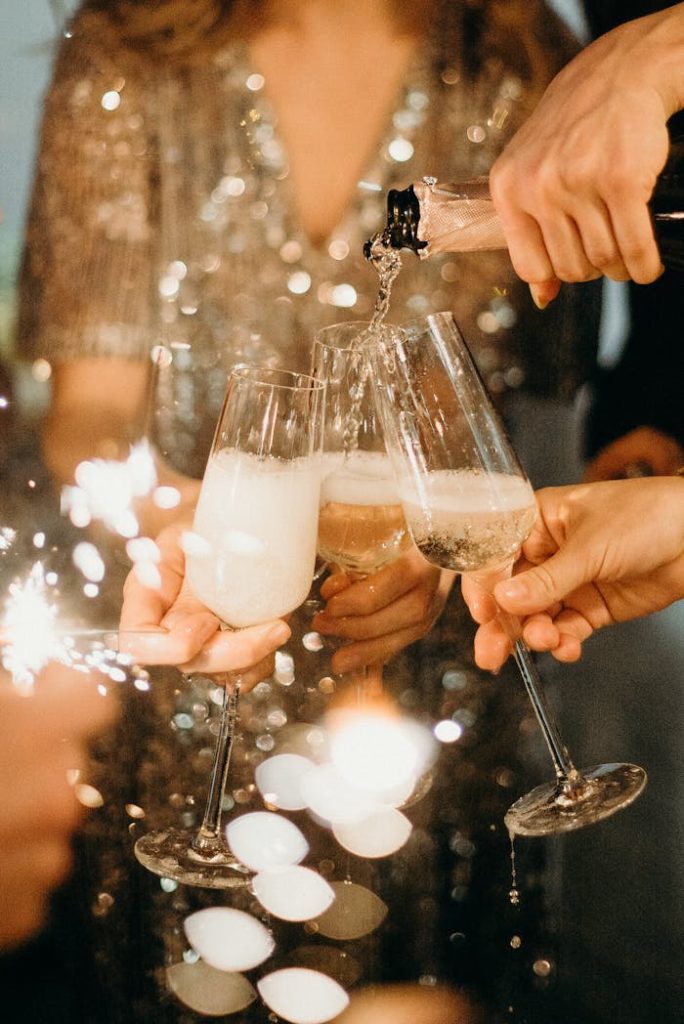 person-pouring-champagne-on-champagne-flutes-3171770 People toasting with champagne glasses amidst sparklers at a festive party.
